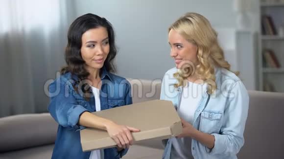 两个微笑的年轻女子打开巨大的披萨盒家庭聚会送食物视频的预览图