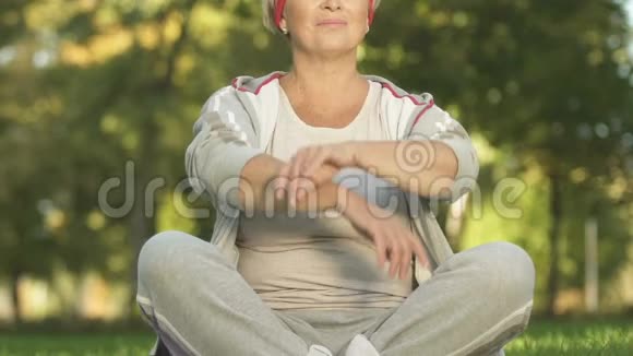 中年妇女在公园里打坐呼吸锻炼锻炼后放松视频的预览图