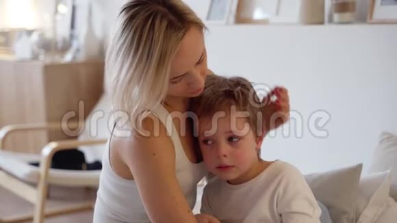 年轻的母亲在卧室拥抱一个哭泣的男孩视频的预览图