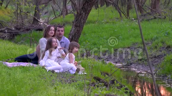 幸福的一家人在河边的公园里休息视频的预览图