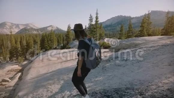 镜头跟随年轻的旅游女孩独自徒步旅行背包在惊人的白色岩石在约塞米蒂公园美国慢动作视频的预览图