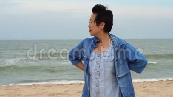时尚自信的亚洲高级女性穿着牛仔裤在海洋中跳跃视频的预览图