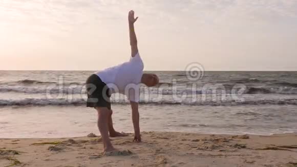 男子站在瑜伽姿势在海边晨练视频的预览图
