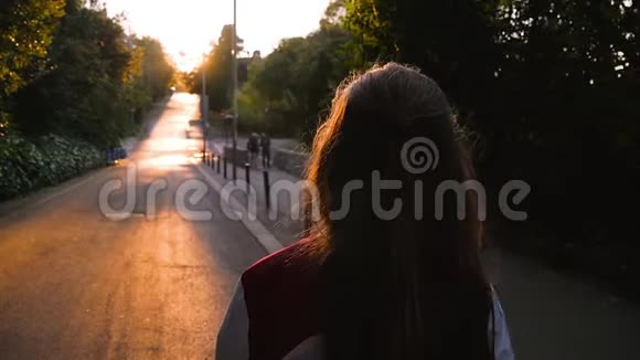 年轻的金发少女在惊人的日落中行走漂亮的女孩微笑着进入镜头露出美丽的金色头发温暖的灯光视频的预览图