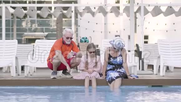 幸福成熟的夫妇和他们的小孙女坐在池边奶奶爷爷还有视频的预览图