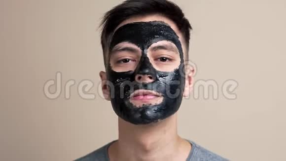 戴着黑色化妆面具的漂亮年轻人用慢镜头视频肖像面部护理自拍视频看镜头视频的预览图