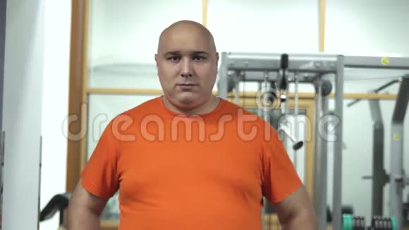 一个穿着橙色t恤的胖帅哥站在体育馆里看起来像个调情者视频的预览图