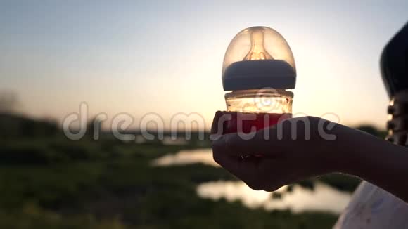 日落时分一个女孩拿着一个婴儿瓶上面写着大自然的背景视频的预览图