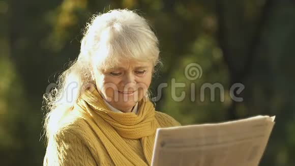 老妇人在报纸上读到有关养老金改革的好消息在公园休息视频的预览图