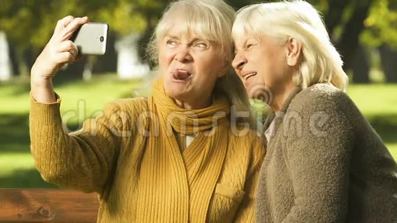 快乐的老女人在手机上展示鬼脸自拍应用快乐的在一起时光视频的预览图