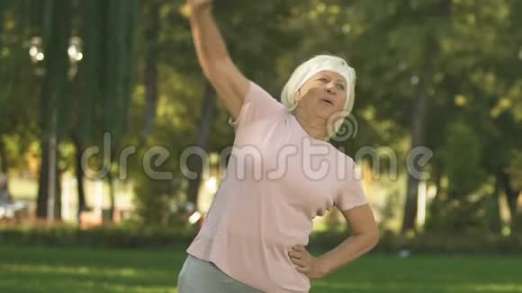 女性退休者在训练前在公园里伸展身体使上半身变暖视频的预览图