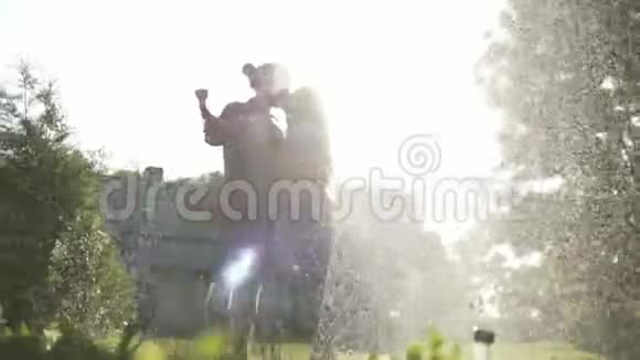 年轻快乐的一对夫妇在花园里吹毛求疵在喷水中玩耍视频的预览图