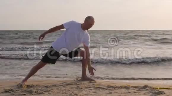 沙滩上海浪背景下练习瑜伽体式的男人视频的预览图