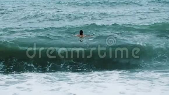 人在暴风雨中在海里游泳在波浪上摇摆慢动作视频的预览图
