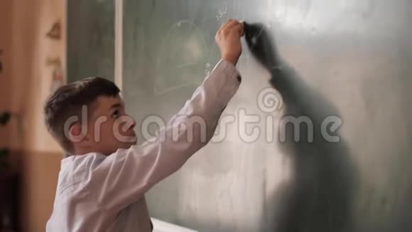 小男孩把黑板上的东西涂成白色聪明的男人视频的预览图