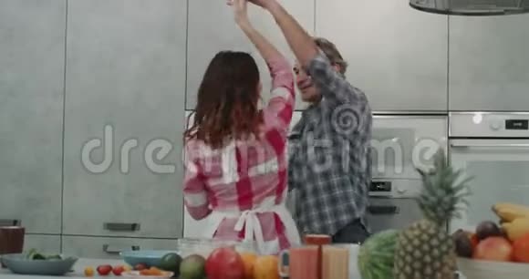 现代灰色厨房有魅力的夫妇在准备食物的时候在顾客面前跳舞视频的预览图