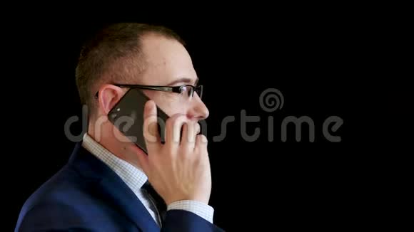 商人把电话带到他耳边打电话穿着黑色背景西装的中年男子的肖像视频的预览图