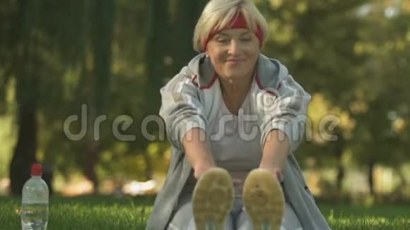 微笑的女人在公园里做伸展运动户外晨练视频的预览图