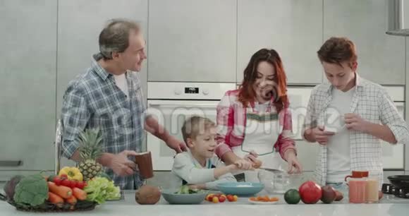 为一对成熟的夫妇和他们的孩子两个男孩做饭周末一起准备一些煎饼现代的视频的预览图