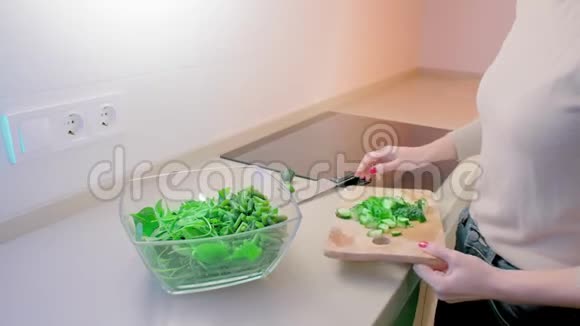 动作缓慢一个未被认出的女人把切好的黄瓜倒在木板上放进一个玻璃沙拉碗里里面有一个大厨房视频的预览图