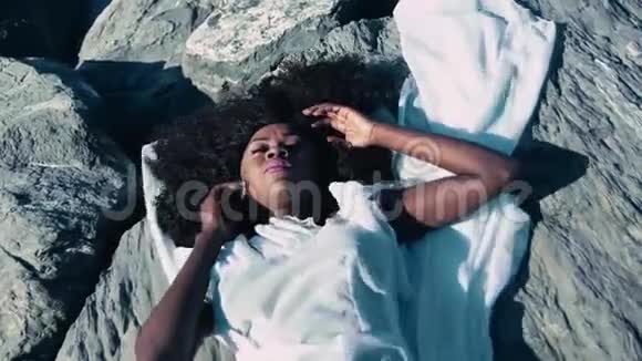 躺在岩石上的黑人女孩视频的预览图