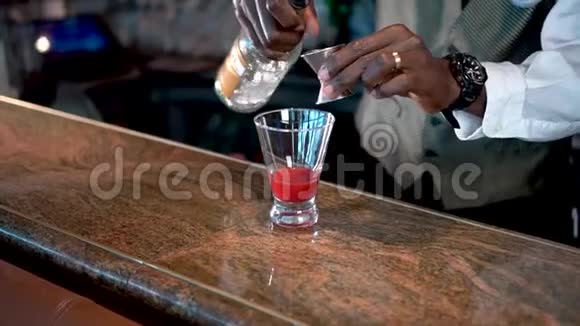 酒保把酒精倒入杯中柜台上有草莓糖浆熔岩流鸡尾酒视频的预览图