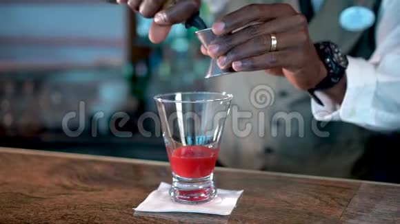 酒精倒进杯里柜台上放着草莓糖浆熔岩流鸡尾酒视频的预览图