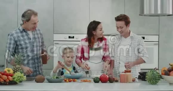成熟的父母和他们的两个男孩一起在厨房做饭都很开心心情也很好视频的预览图