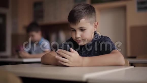 可爱的小男孩在上课时使用电话两个学生视频的预览图