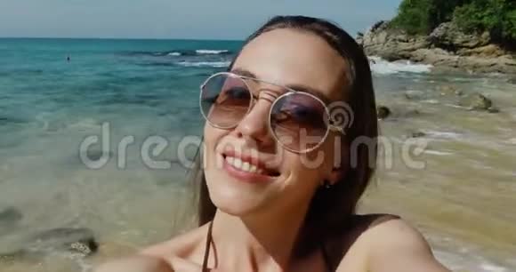 美女在沙滩上用手机自拍视频的预览图