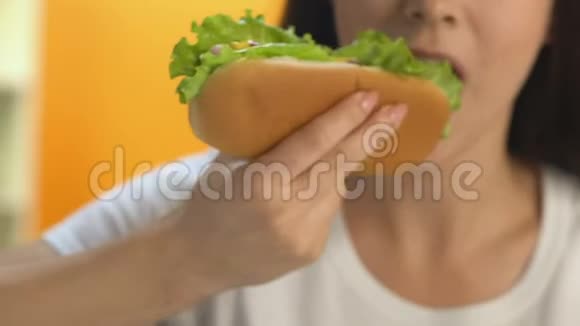 女性午餐时间吃高热量热狗高脂肪快餐节食视频的预览图