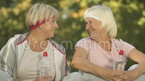 女性退休老人在镜头前看着坐在公园里拿着水瓶视频的预览图