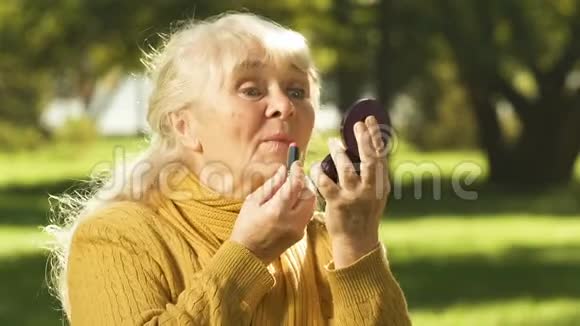 老年妇女涂口红向朋友吹嘘抗衰老的化妆品视频的预览图