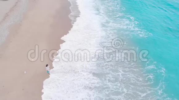 美丽的女人站在沙滩上的浪花里视频的预览图