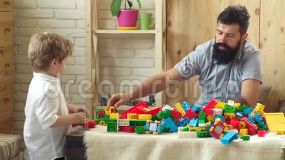 有着快乐面孔的父子用玩具砖创造了五颜六色的建筑那男孩和他父亲一起玩视频的预览图