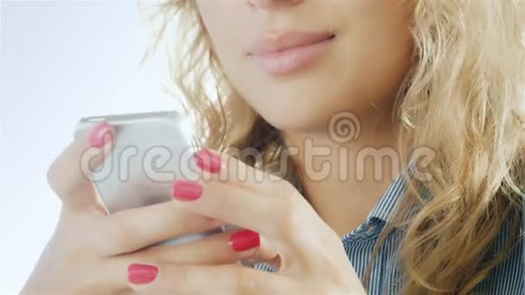 女人在智能手机上打字微笑着特写的手在相框里可以看到用手机和嘴唇合在一起视频的预览图