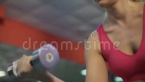 强壮的运动女士训练手臂肌肉在健身房用哑铃锻炼视频的预览图