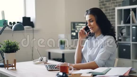 漂亮的女员工在办公室用手机聊天用笔记本电脑视频的预览图
