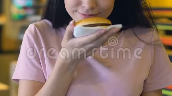 微笑的女人在镜头前展示美味可口的汉堡肥胖的风险视频的预览图