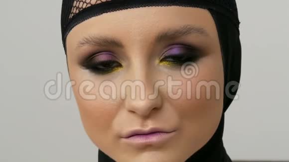 年轻的职业女孩模特漂亮的妆容和棕色的眼睛头前戴着一顶黑色的帽子视频的预览图