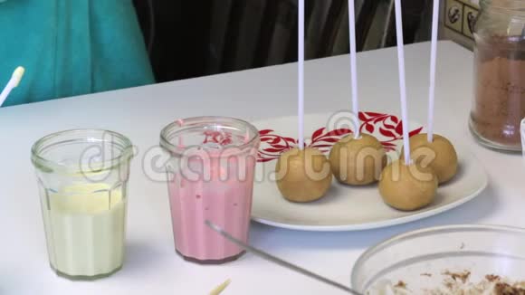 那个女人把筷子插在海绵球里做流行蛋糕桌子附近有带糖霜的眼镜视频的预览图