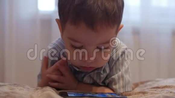 特写小宝贝小男孩站在床边看手机快乐的童年视频的预览图