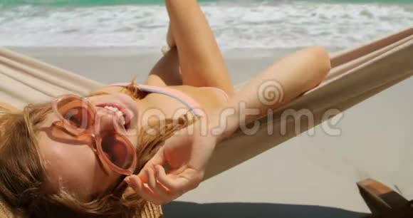 高加索女人在海滩4k吊床上放松的后景视频的预览图