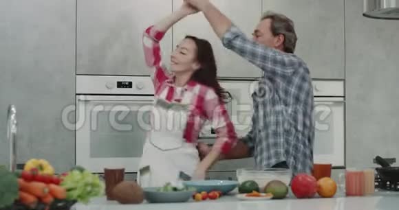 非常漂亮的成熟夫妇在厨房里度过浪漫的时光同时做食物并有一个好心情4k视频的预览图