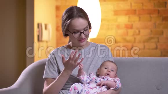 母亲在客厅里和她可爱的新生女儿谈话的肖像视频的预览图