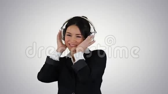 年轻的商务女性在耳机里听音乐在梯度背景下跳舞视频的预览图