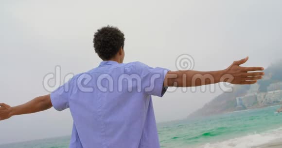 非裔美国人男子的后景双臂伸展在海滩上视频的预览图