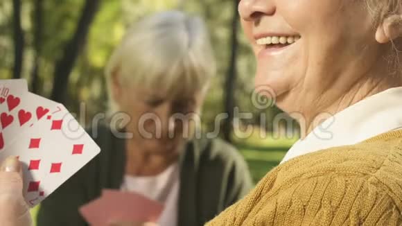 微笑的高级女性与朋友在外面打牌退休自由时间视频的预览图