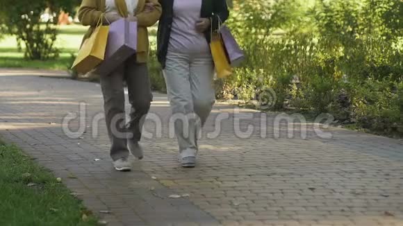 在公园里和购物袋一起散步的老年女性视频的预览图