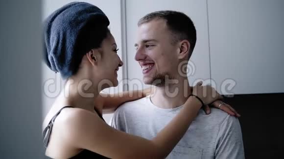 一个穿着家居服的帅哥抱着他微笑的女朋友坐在厨房的窗台上年轻女子视频的预览图